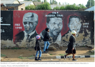 Residents of Soweto walk past a wall bearing painted portraits of former South African President Nelson Mandela in Soweto. Photo: AFP/ALEXANDER JOE 