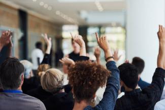 photo of group of people raising their hands to question