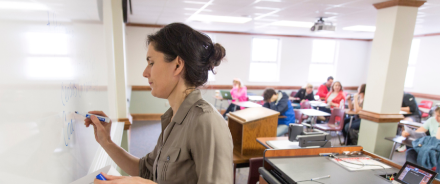 Working environmental portrait of Distinguished Research Professor Awards winner Susan Mattern writing notes on the board during her Ancient Rome history class inside LeConte Hall.