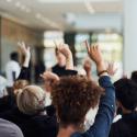 photo of group of people raising their hands to question